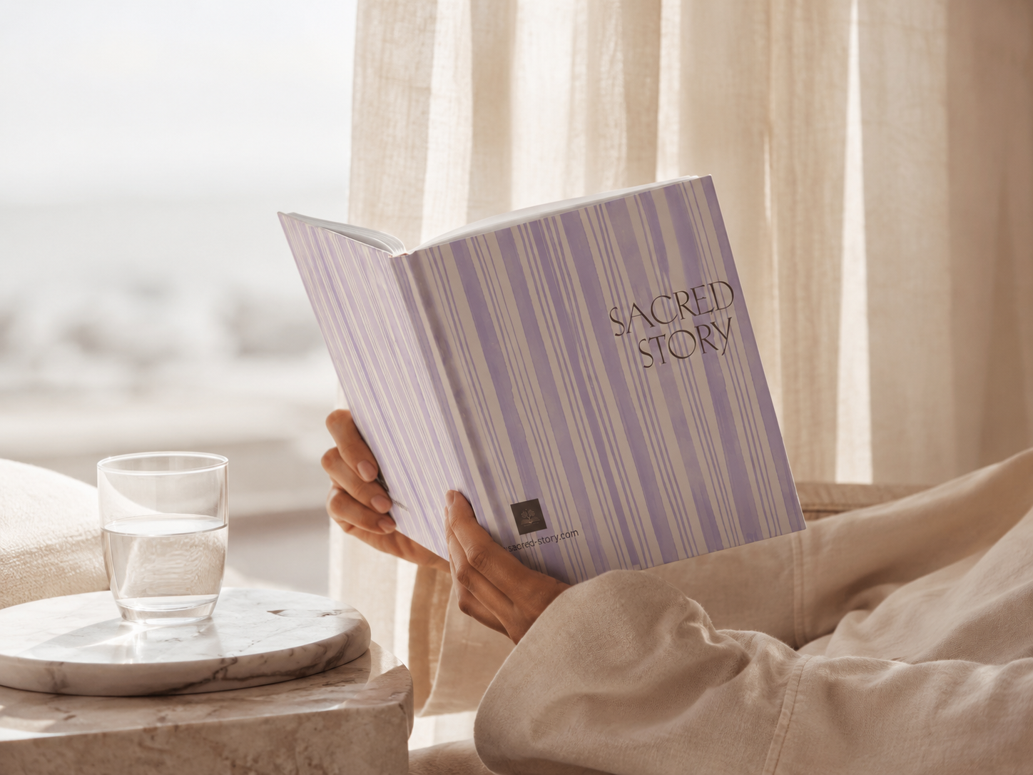 A reader holding the Coastal edition of Sacred Story in soft natural light.